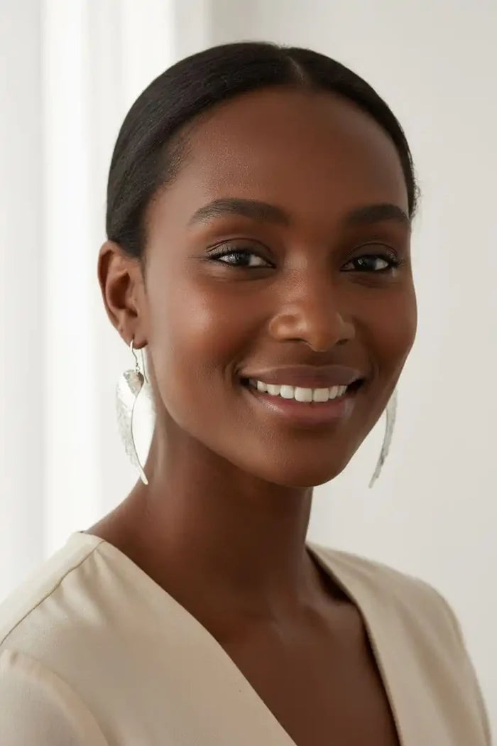 Silver Hammered Sculpted Angel Wing Earrings worn by a smiling woman with dark hair.