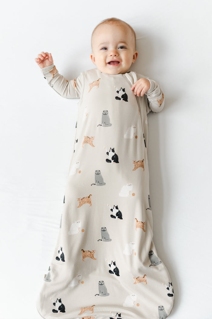 Baby in a 0.5 sleep bag with a cat pattern on a white background