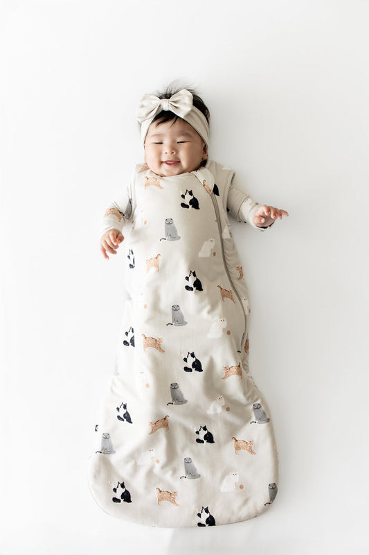 Smiling infant wearing he Sleep Bag in Fluffy Cat 1.0 with matching romper on underneath