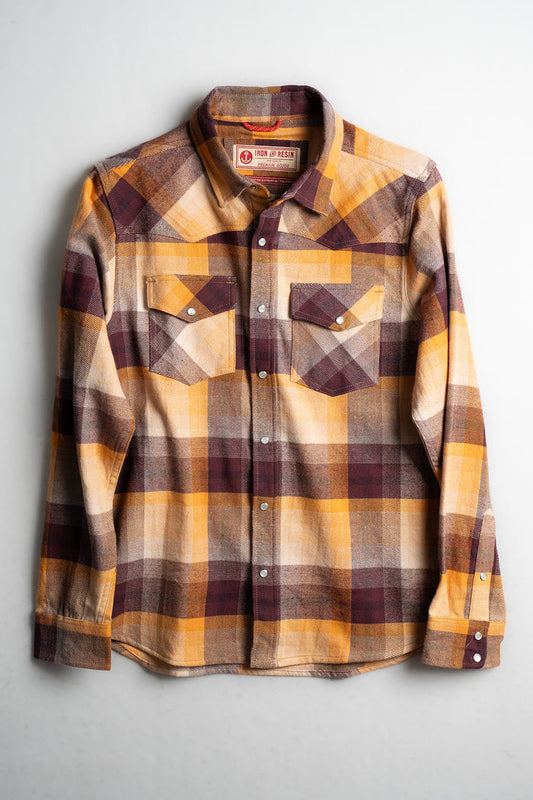 Plaid flannel shirt in yellow, brown, and cream tones with buttoned pockets, displayed flat on a white background.