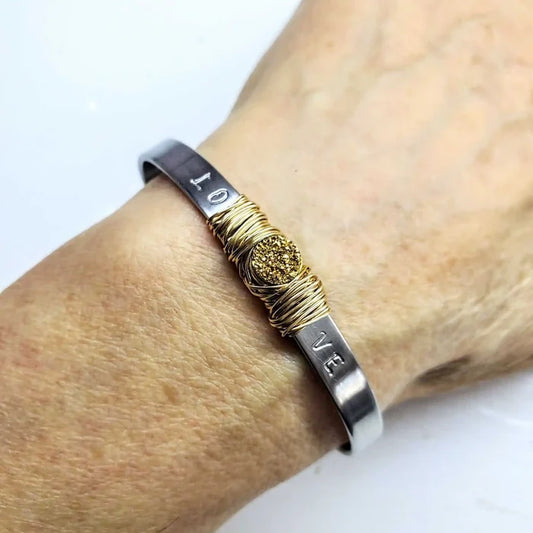 Stainless Steel LOVE Stamped Wire Wrapped Gold Druzy Cuff worn on a wrist, showcasing its elegant design and craftsmanship.