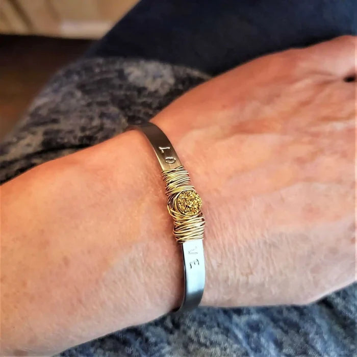 Stainless Steel LOVE Stamped Wire Wrapped Gold Druzy Cuff worn on a wrist, showcasing its unique design and elegance.