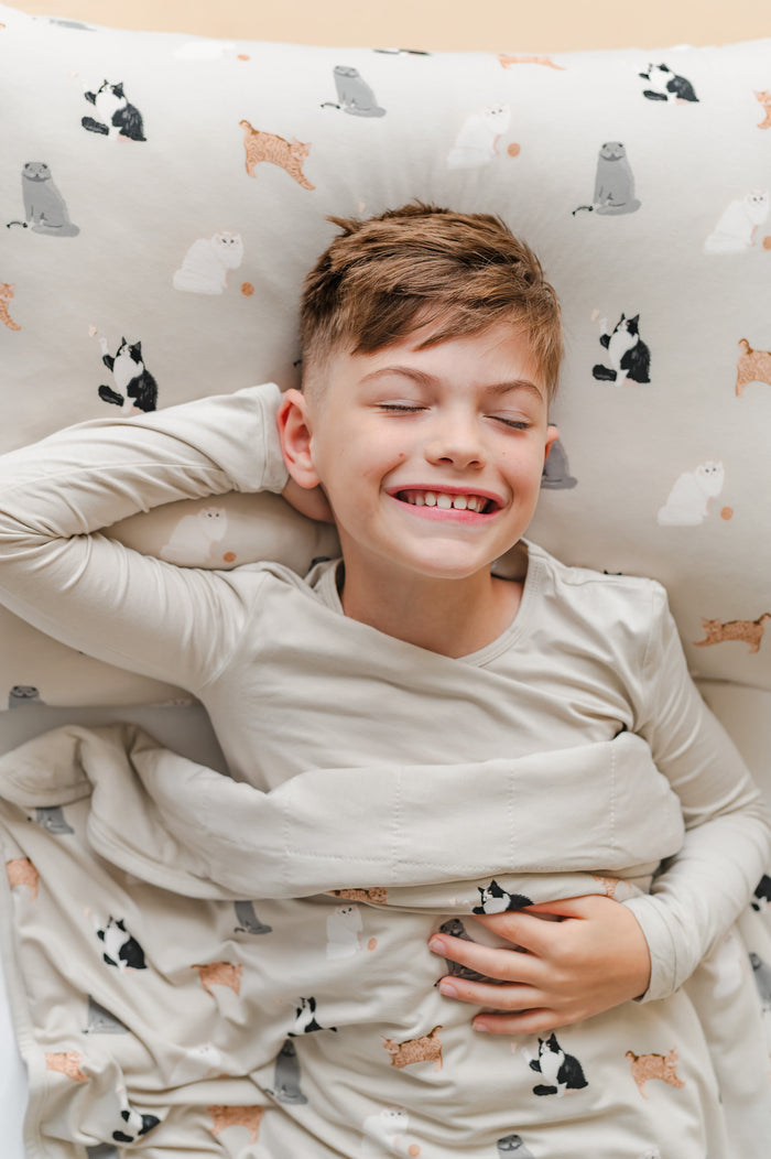 Boy sleeping on a standard pillow with a cat patterned pillow case and matching blanket