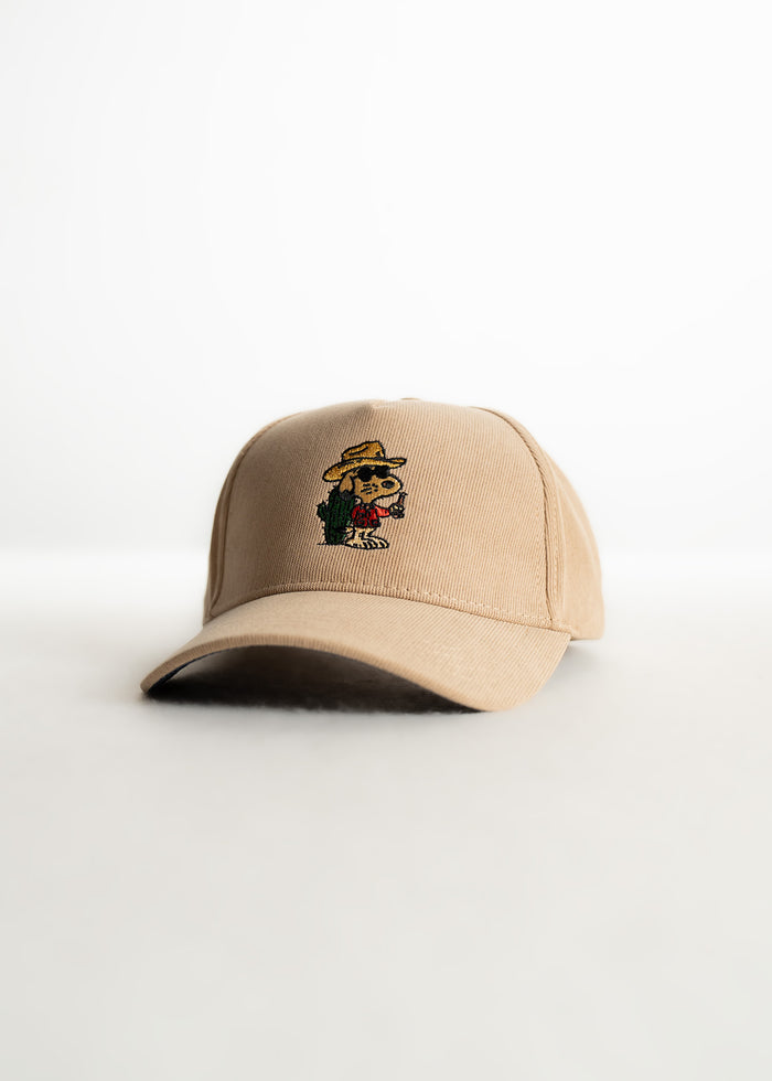 Tan baseball cap with embroidered cartoon character wearing a hat, holding a drink, and standing by a cactus on a white background.