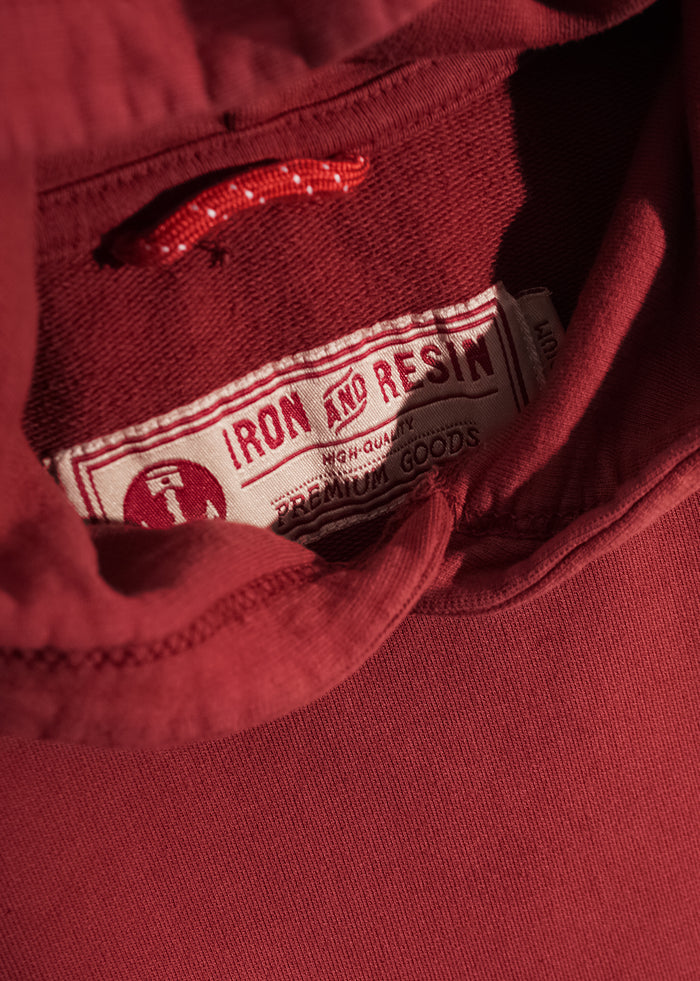 Close-up of a red hoodie with an "Iron and Resin" label, highlighting premium goods and quality craftsmanship.