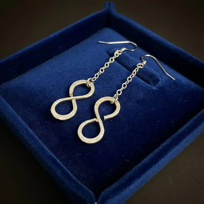 Sterling Silver Hammer Patterned Infinity Earrings displayed in a blue velvet box, showcasing elegant craftsmanship.