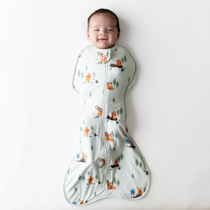 Smiling infant wearing the Swaddle Bag in Winnie the Pooh Hundred Acre Wood 0.5