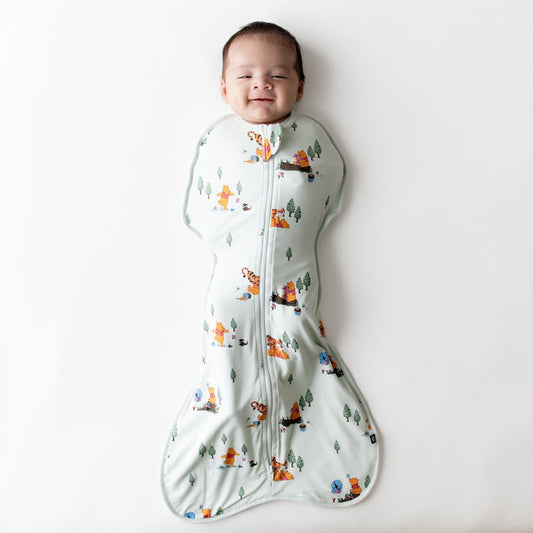 Smiling infant wearing the Swaddle Bag in Winnie the Pooh Hundred Acre Wood 0.5