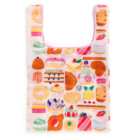 The Emily Taylor Sweet Confections Packable Nylon Tote Bag features a colorful pattern of cakes, donuts, and tarts on a cheerful light pink background. Made from eco-friendly nylon and designed for reuse.