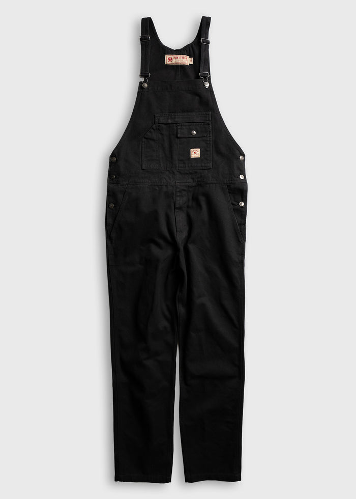 Black overalls with adjustable straps and front pocket, displayed on a white background, emphasizing classic workwear style.
