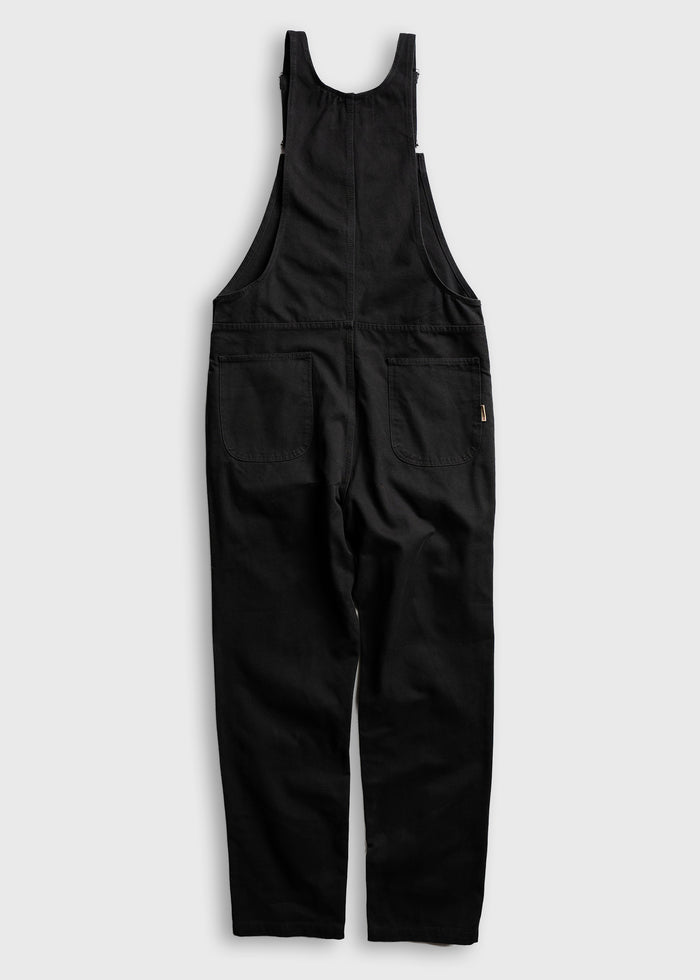 Black overalls with wide straps and two large back pockets, displayed on a light gray background, showcasing casual style.
