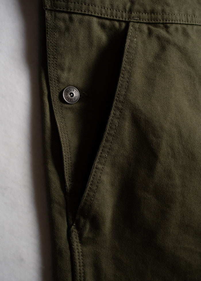 Green work overalls showcasing durable fabric, utility pockets and custom buttons.
