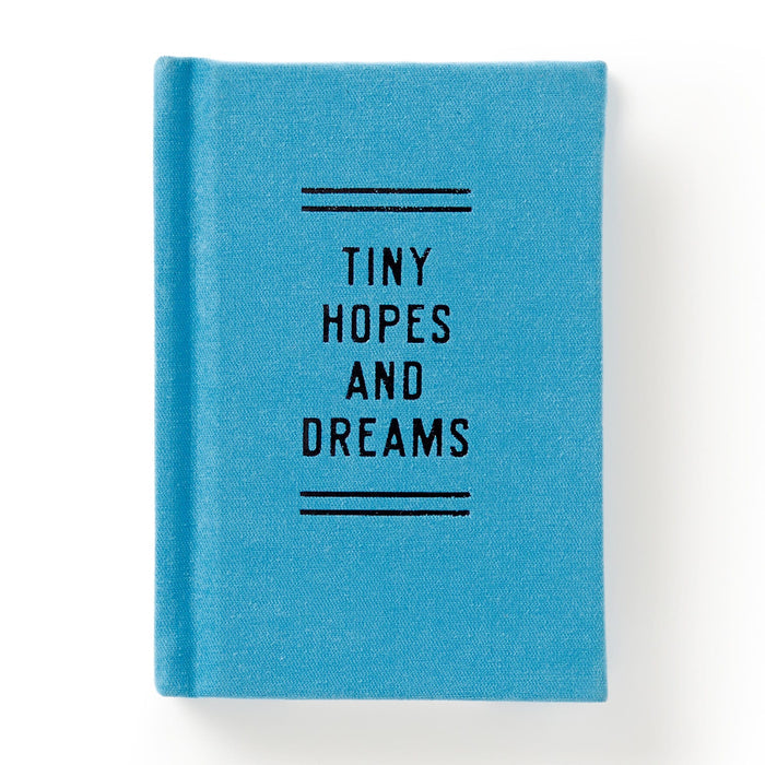The Brass Monkey Tiny Hopes and Dreams Tiny Diary is a small, blue hardbound notebook with Tiny Hopes and Dreams in black on the cover, along with decorative lines. Photographed against a white background.