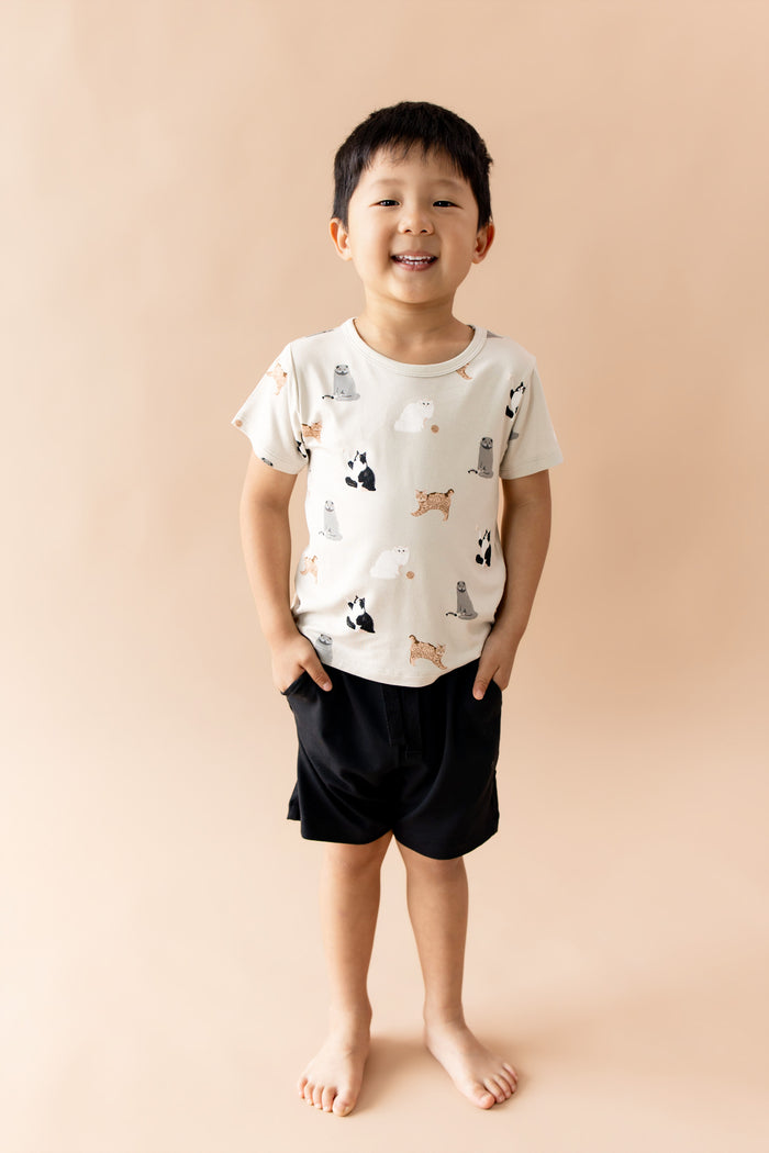 Smiling boy wearing the Toddler Basic Tee in Fluffy Cat paired with black shorts