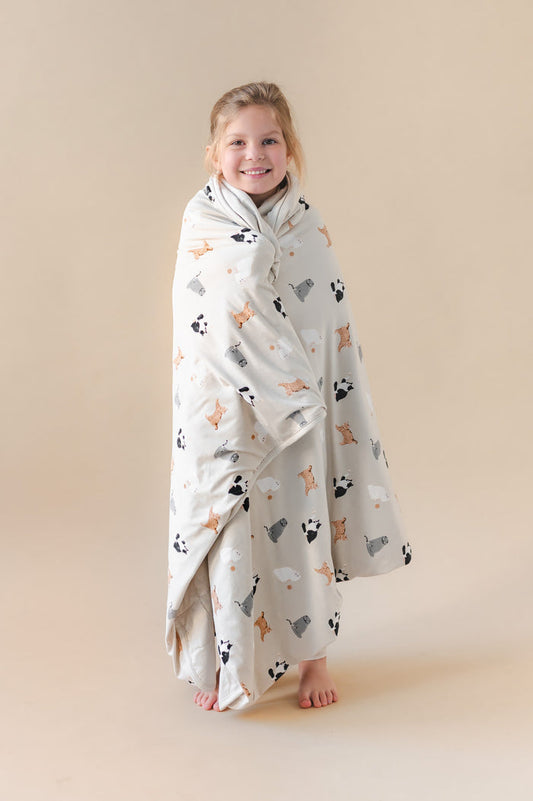 Child wrapped in a blanket with cat prints on a beige background