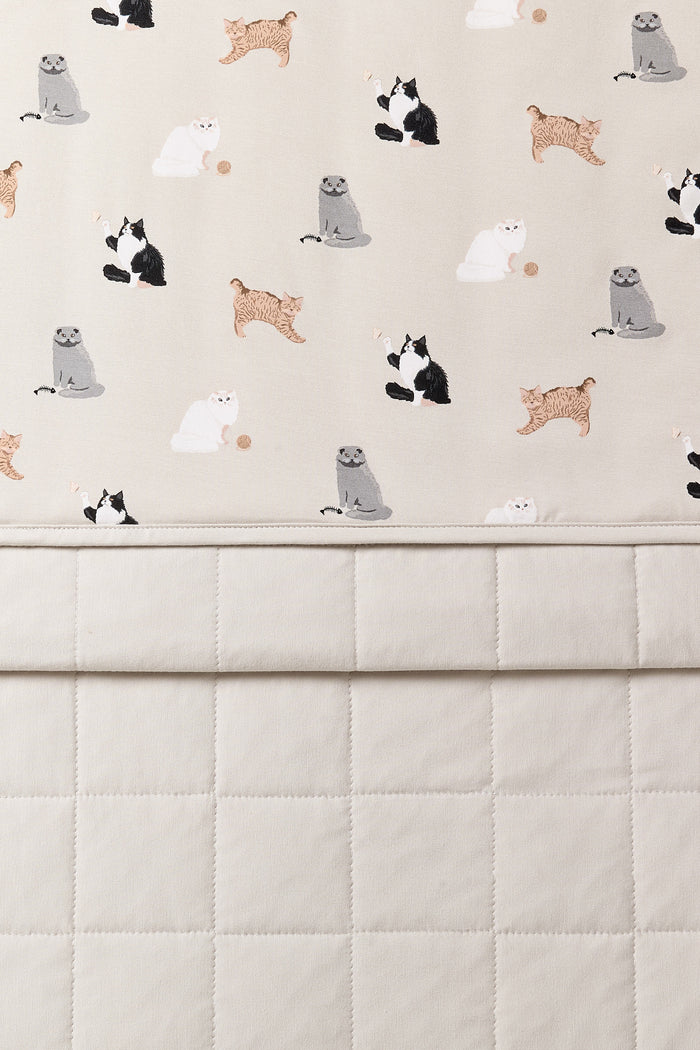 Close up of the Toddler Blanket in Fluffy Cat 1.0 showing the light beige quilted backing and smooth top layer cat print