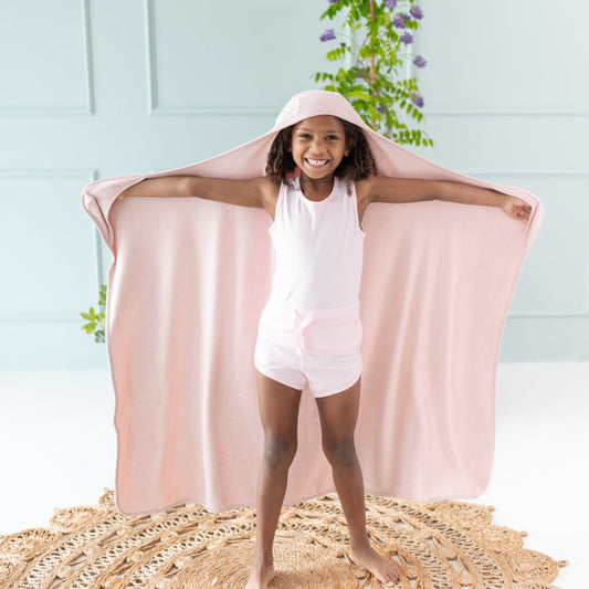 Girl holding Kyte Baby Hooded Bath Towel with pocket inserts in Blush