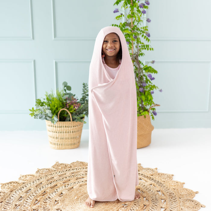 Child wrapped in Kyte Baby Toddler Hooded Bath Towel in Blush pink