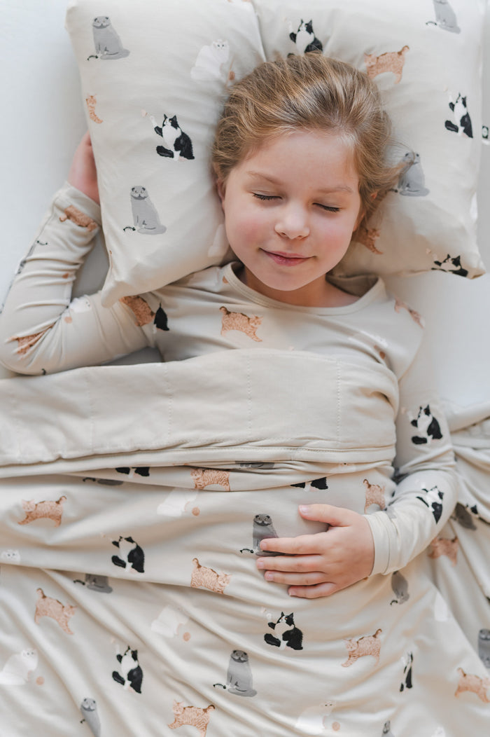 Young girl sleeping with a pillow and blanket that have a cat pattern
