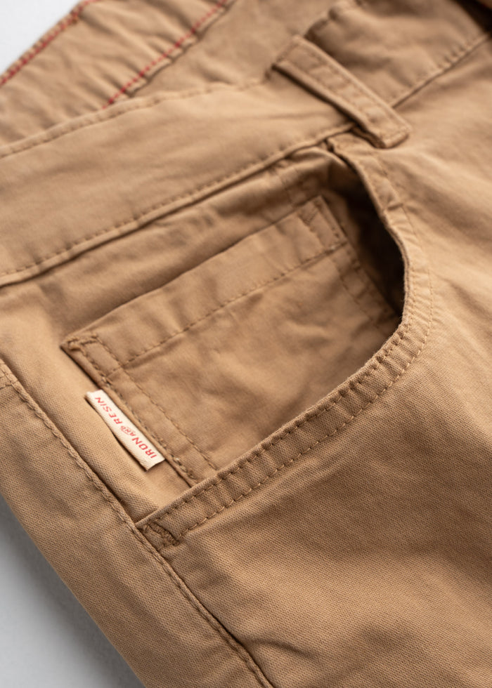 Close-up of tan pants pocket with detailed stitching and a small "Iron & Resin" label, showcasing craftsmanship and design.