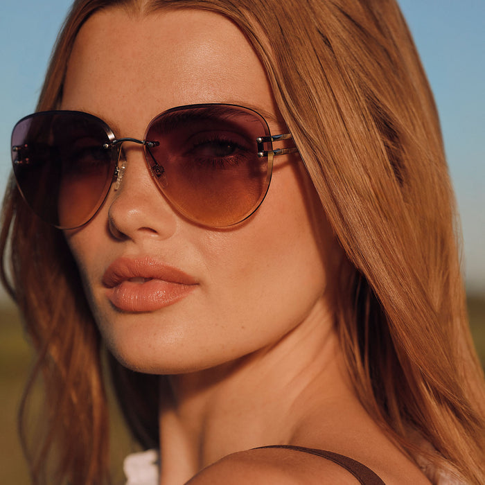 lifestyle - female outdoors wearing diff eyewear featuring the trista aviator sunglasses with a gold frame and misty lilac gradient lenses close up view