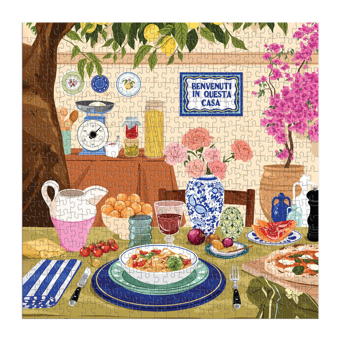 Enjoy Ana Hard’s Tuscan Afternoon 500 Piece Puzzle, featuring a vibrant Italian outdoor meal scene with pasta, bread, fruit, drinks, flowers, and a Benvenuti in questa casa sign—perfect for fans of scenic puzzles.