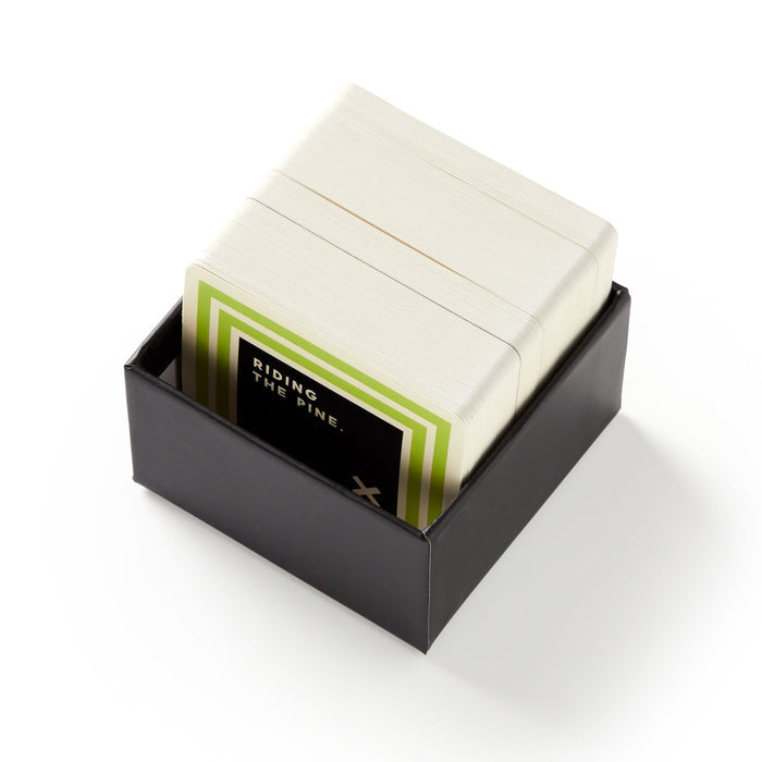 Brass Monkeys Weird Sports Trivia is a black box of trivia cards for fans of unusual sports facts. The top card has a green border, black center, and reads RIDING THE PINE. Displayed on a white surface.