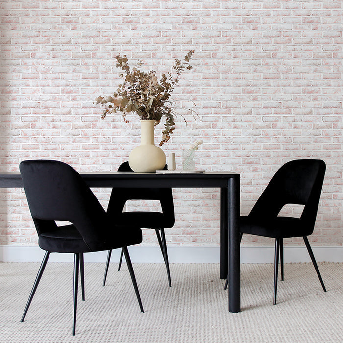 Tempaper's Whitewashed Brick Peel And Stick Wallpaper shown behind a black table with a plant on top and black chairs.  #color_whitewashed