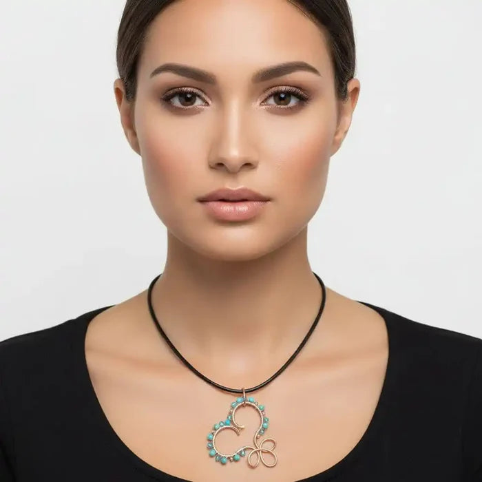 Wire Wrapped Copper Turquoise Heart Infinity Charm Necklace displayed on a model featuring turquoise beads and a copper design.