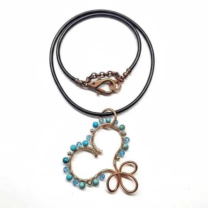 Wire Wrapped Copper Turquoise Heart Infinity Charm Necklace featuring turquoise beads and black leather chain.