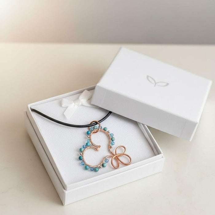 Wire Wrapped Copper Turquoise Heart Infinity Charm Necklace displayed in a gift box with turquoise beads and a copper charm.