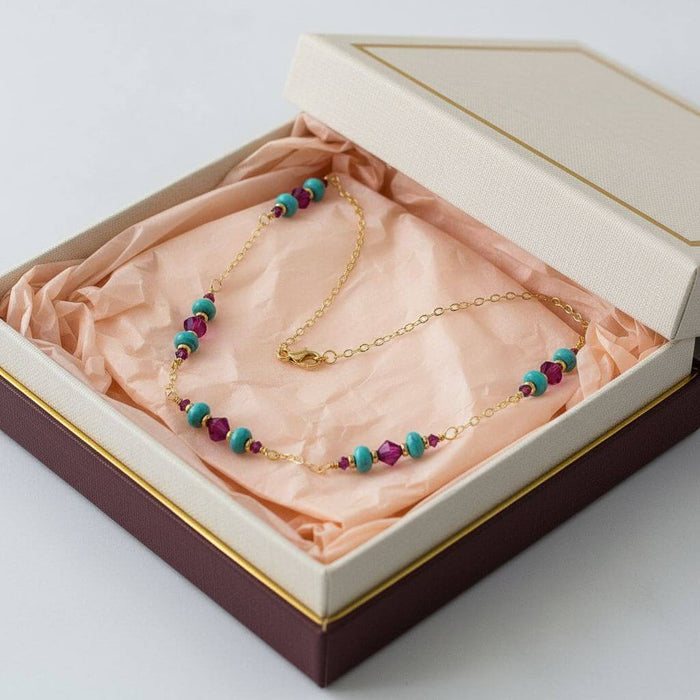 Wire Wrapped Gold Filled Pink Turquoise Gemstone Necklace placed in a gift box with colorful tissue paper.