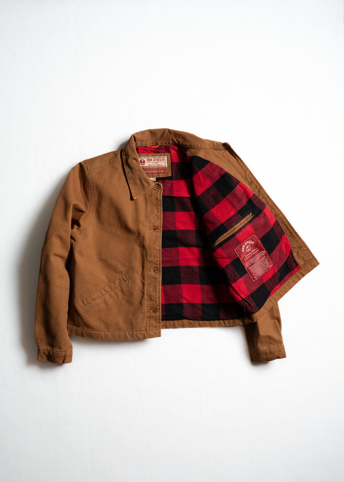 Brown jacket with red and black plaid lining, open to reveal interior label and pocket, displayed on a white background.