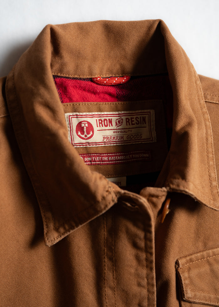 Brown jacket with red lining, featuring an Iron and Resin label. The collar is neatly folded, showcasing premium craftsmanship.