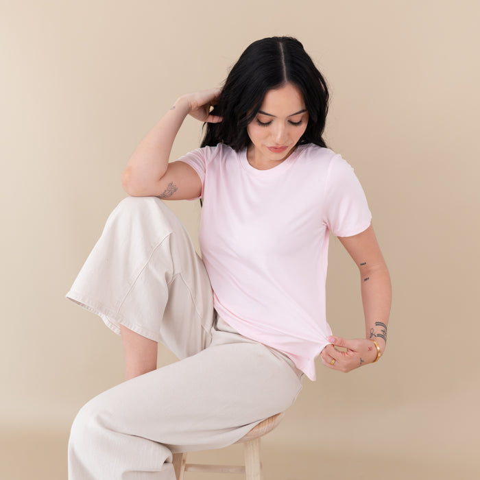 Woman modeling Women's Crew Neck Tee in Sakura sitting on stool