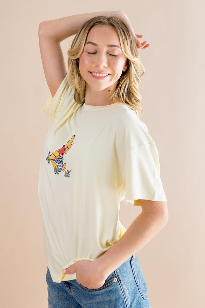 Smiling model posing wearing the Women's Graphic Tee in Winnie the Pooh on Chamomile