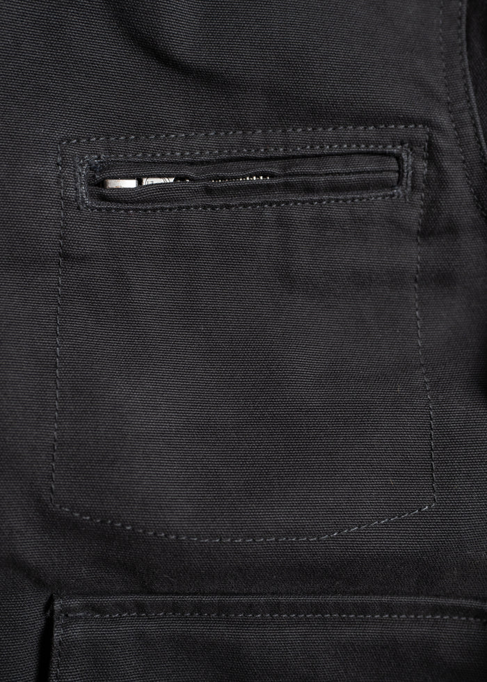 Close-up of a black fabric jacket pocket with a visible zipper, showcasing detailed stitching and texture.