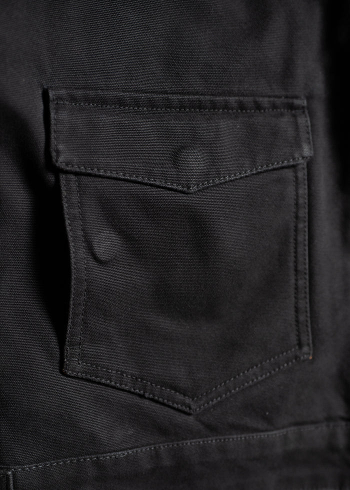 Close-up of a black fabric pocket with a flap, showing detailed stitching and texture, highlighting the material's quality.