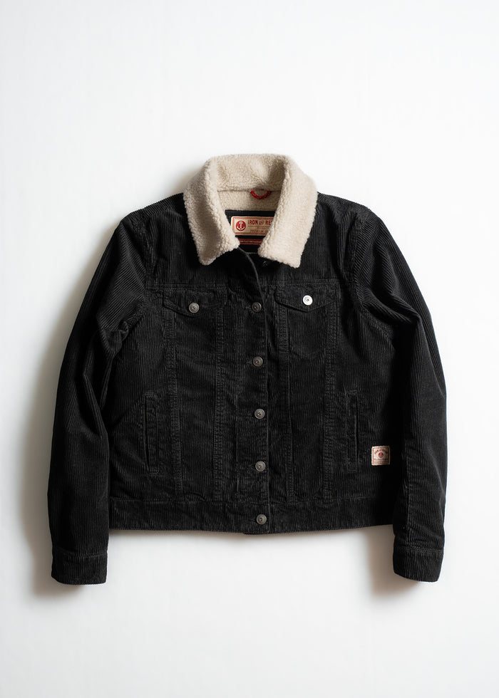 Black corduroy jacket with a beige sherpa collar, buttoned front, and two chest pockets, displayed on a white background.