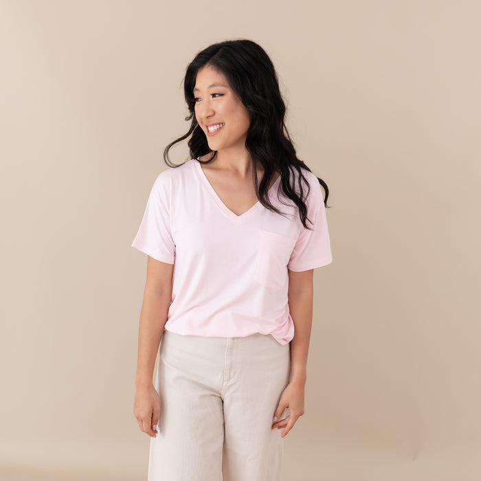 Woman modeling Women’s Relaxed Fit V-Neck in Sakura and linen colored pants against a tan backdrop