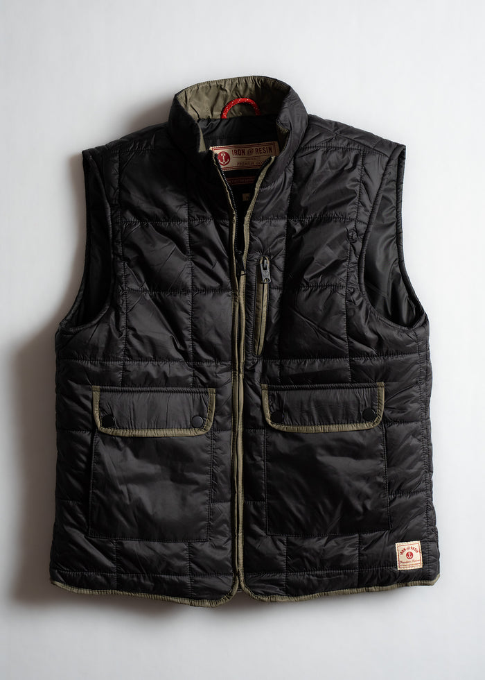 Black quilted vest with two front pockets and a zipper, featuring Iron & Resin branding on the collar, laid flat on a white surface.