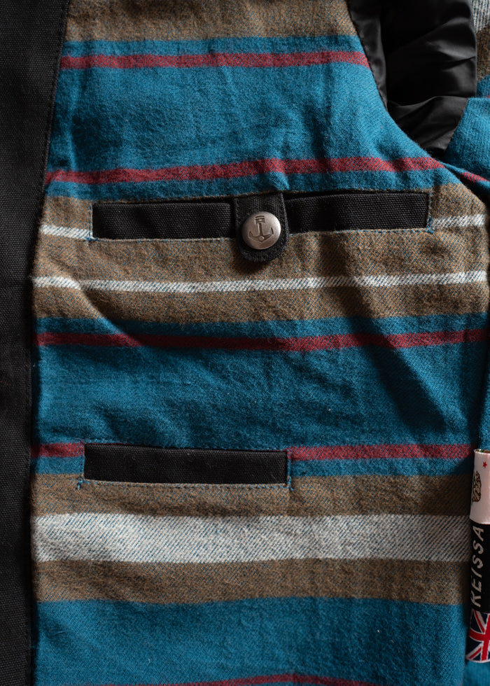 Striped fabric with teal, brown, and red hues features two black pockets and a silver button, creating a stylish pattern.