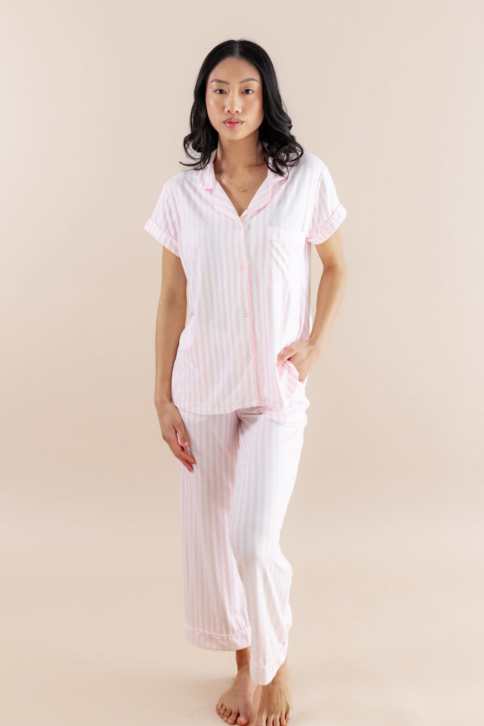 Woman wearing a pink striped pajama set against a beige background