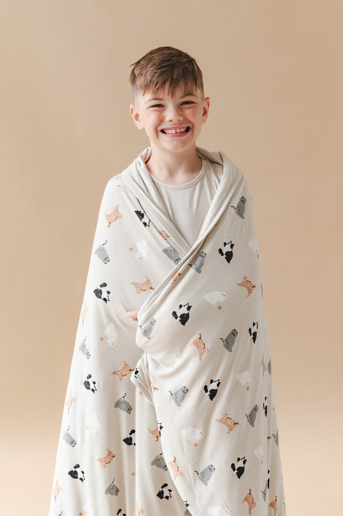 Child wrapped in a blanket with cat prints against a beige background